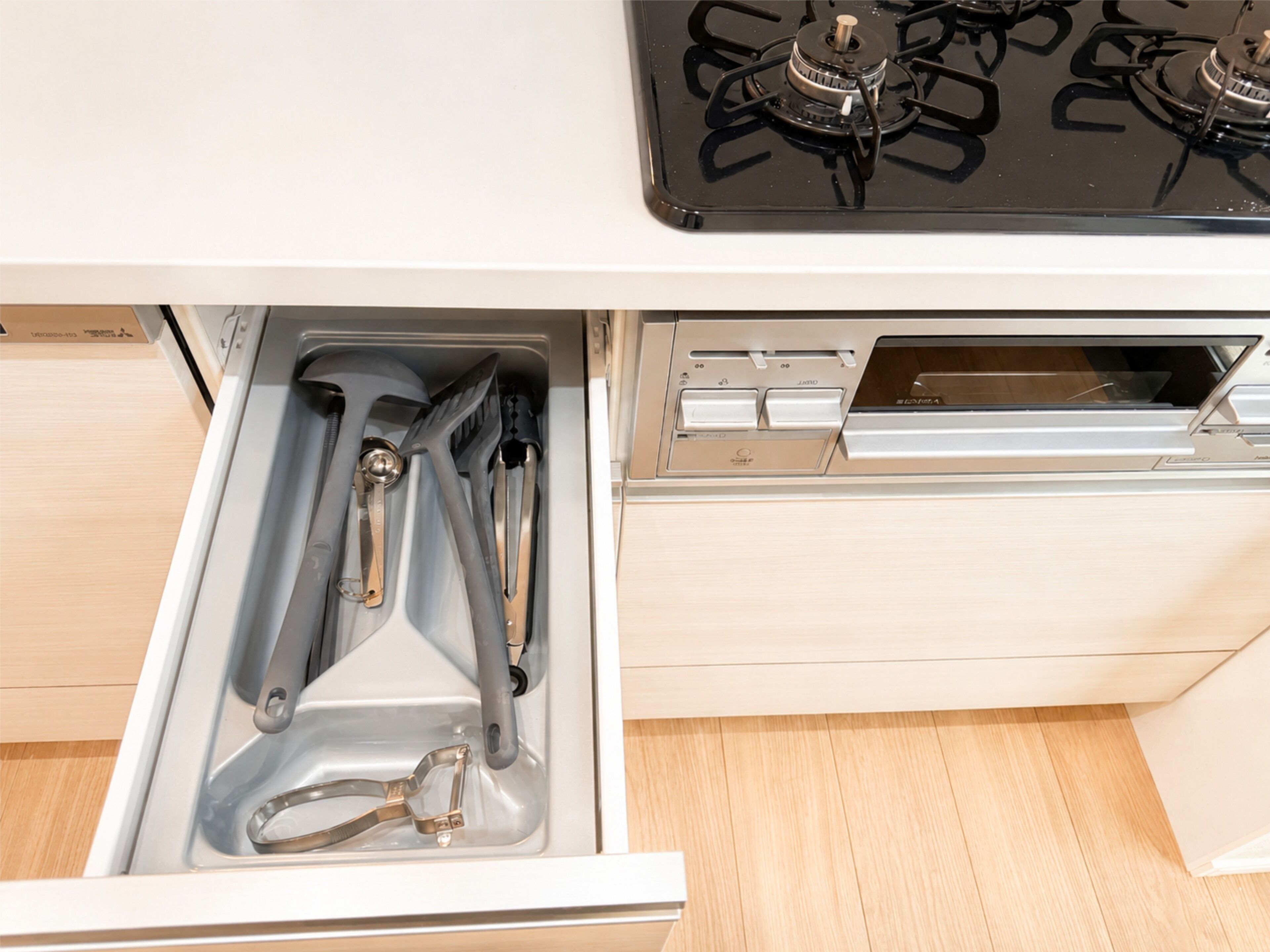 A kitchen drawer with utensils and a stove top.