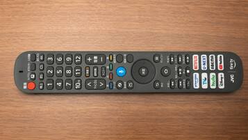 A remote control with various buttons and symbols, including numbers, directional arrows, and brand logos.