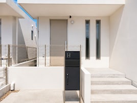 Um edifício moderno com cerca de metal, uma porta e uma escadaria que dá acesso a um andar superior.
