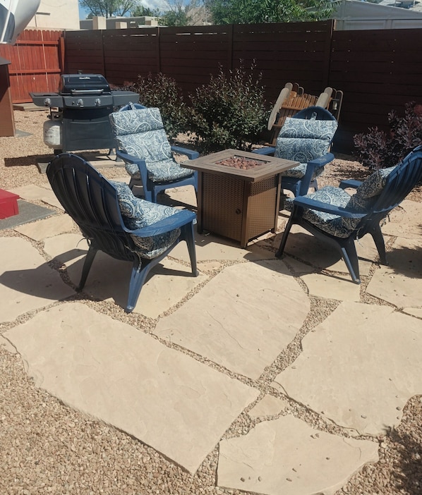An outdoor patio with stone flooring, a central square table, and four patterned chairs.