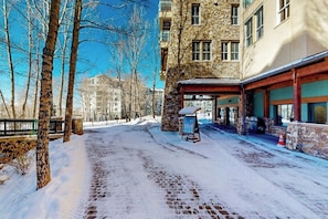 Eine verschneite Straße mit einem Steinhaus, einem Hauseingang und einem Schild.