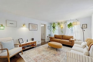 Ein Wohnzimmer mit einer Couch, Sesseln, einem Couchtisch und einer Stehlampe.