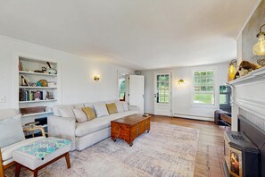 Ein geräumiges Wohnzimmer mit einem weißen Sofa, einer Holzkiste und einem Kamin.