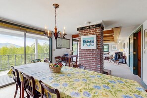 A dining area with a table set for four, a chandelier, and a sign indicating a ski trail. - Peaceful mountain home w/ amazing views; close to hiking trails & quaint towns (Franconia)