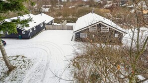 A snow-covered property with two buildings, a fenced yard, and a clear sky. - 4 Star Holiday Home in Knebel (Knebel)