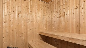 A wooden sauna with benches and a stone heater. - 4 Star Holiday Home in Knebel (Knebel)