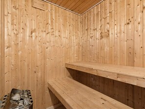 Eine Holzzimmer-Sauna mit Bänken und einem Steinofen.