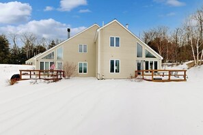 A two-story house with a large front porch, a chimney, and a snow-covered driveway.