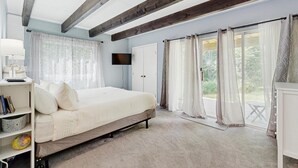 Ein Schlafzimmer mit einem Bett, einem Fernseher, einem Bücherregal und einem Fenster mit Vorhängen.
