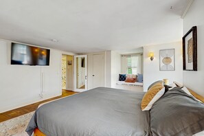 Ein Schlafzimmer mit Bett, Fernseher, Spiegel und Fenster.