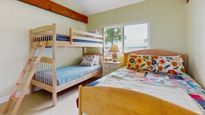 Une chambre avec un lit superposé, une échelle, une table de chevet avec une lampe et une fenêtre donnant sur un beau paysage.