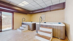 A spa area with hot tubs, wooden steps, and a view through a glass door.