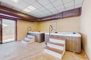 A spa area with hot tubs, wooden steps, and a view through a glass door. - Mt. Snow All Season Condo: w/ shared hot tub & pool, ski shuttle, tennis (Dover)
