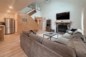 Ein modernes Wohnzimmer mit Sofa, Couchtisch, Kamin, Fernseher und Küchenzeile.