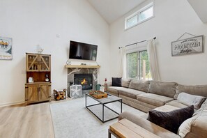 A living room with a fireplace, a sofa, a coffee table, and a television. - Newly renovated mountainside condo on the access road with two suites (Dover)
