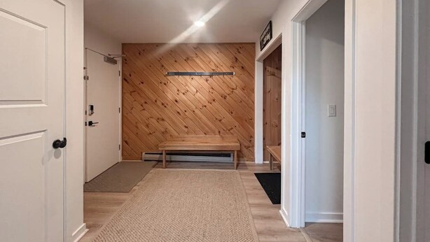 A hallway with a wooden wall, a bench, and a door.