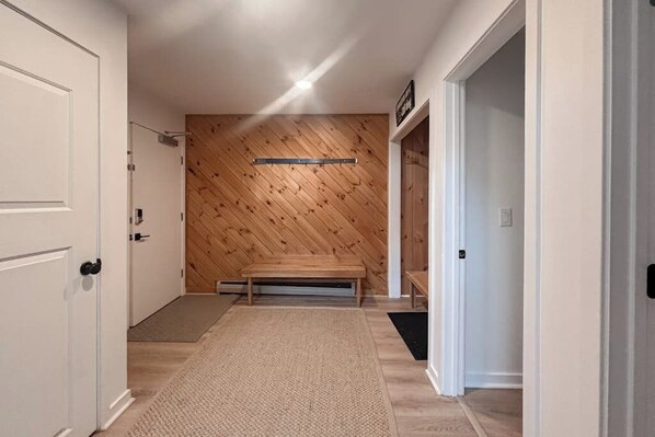 A hallway with a wooden wall, a bench, and a door. - Mt. Snow All Season Condo: w/ shared hot tub & pool, ski shuttle, tennis (Dover)