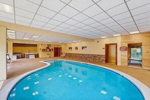 A hotel swimming pool with a tiled ceiling, a stone wall, and a sauna area. - Mt. Snow All Season Condo: w/ shared hot tub & pool, ski shuttle, tennis (Dover)