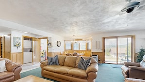 A living room with a sofa, a coffee table, and a dining area with a table and chairs. - White Mountain Condo: close to ski, hiking, local attractions, dining & views (Bartlett)