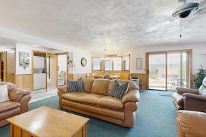 A living room with a sofa, a coffee table, and a dining area with a table and chairs. - White Mountain Condo: close to ski, hiking, local attractions, dining & views (Bartlett)