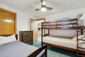 A room with a bunk bed, a single bed, a wooden wardrobe, and a ceiling fan. - Condo with gas fireplace and hiking trails at the door, near Story Land (Bartlett)