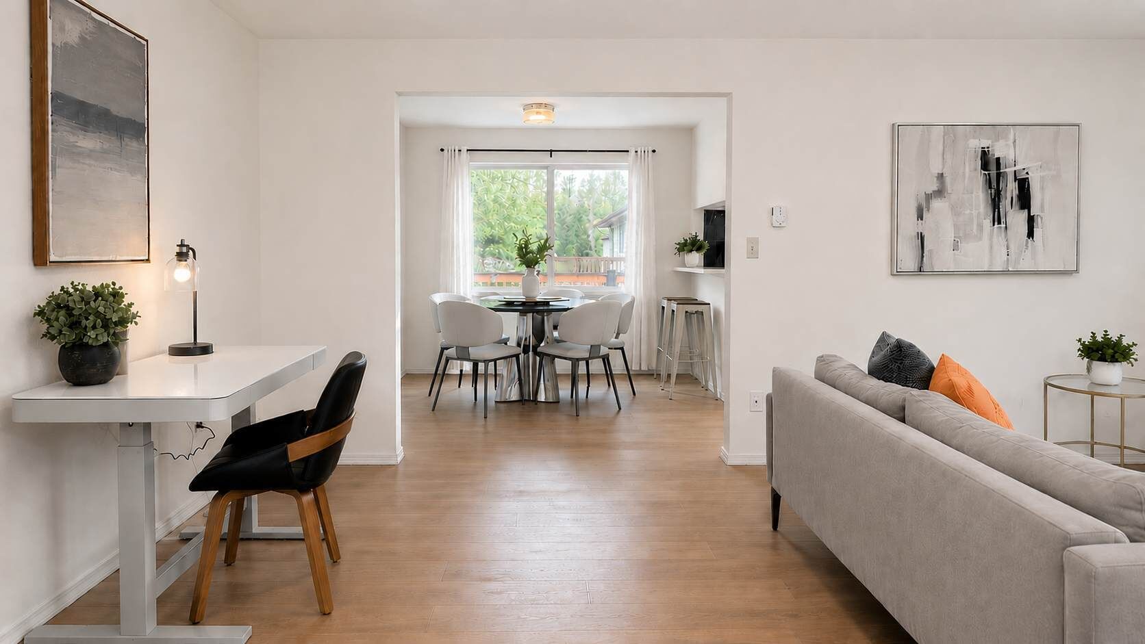 Een moderne woonkamer met een bank, een eettafel, stoelen en een bijzettafeltje met een plant.