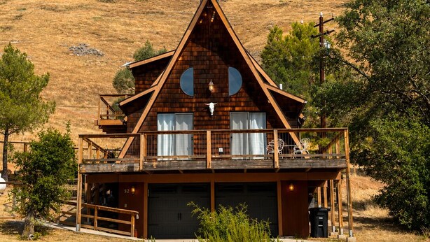 Een houten chalet met balkon, garage en een berg op de achtergrond.