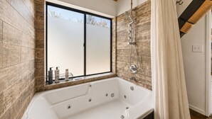 Een moderne badkamer met een groot bad, een douche en een raam met uitzicht.