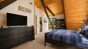 Een slaapkamer met een bed, een televisie, een dressoir en een bordje met de tekst 'GO Hike'.