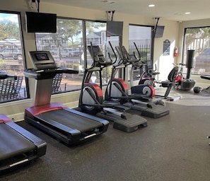 Ein Fitnessstudio mit Laufbändern, Crosstrainern und Kraftgeräten.