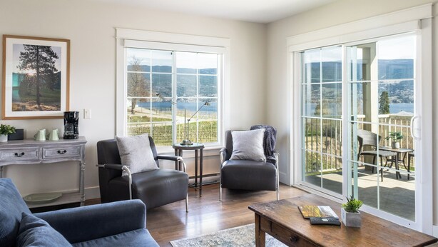 A living room with a view of a vineyard, a coffee station, and a seating area with a table and chairs.
