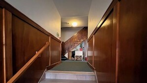 A staircase with wooden railings leading to a landing area with a table and chairs. - Sherman Hills Historic Retreat #6 (Des Moines)