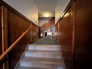 Eine Treppe mit hölzernen Geländern führt zu einer Zwischenebene mit Tisch und Stühlen.