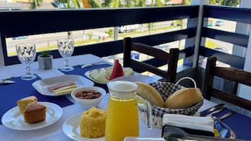 Una mesa dispuesta con comida y bebidas, con vistas a un paisaje urbano y zonas verdes.