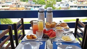 Una mesa lista para el desayuno con vista a la montaña, que incluye platos, cubiertos y un frutero.