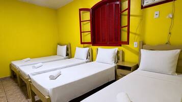 A hotel room with four single beds, a red-framed window, a wall-mounted air conditioner, and a tiled floor.