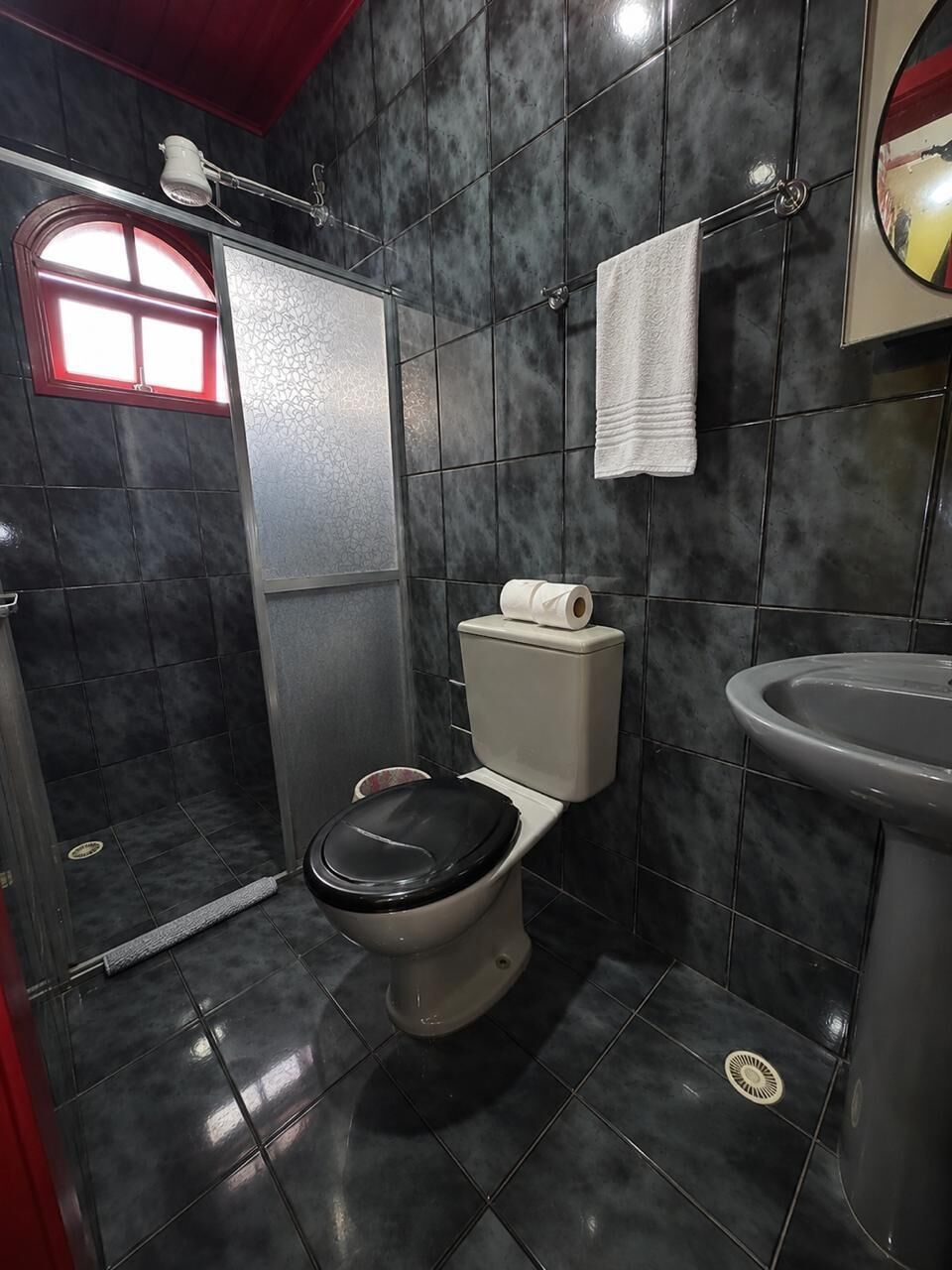Een badkamer met toilet, wastafel, een handdoek aan een rek en een douche.