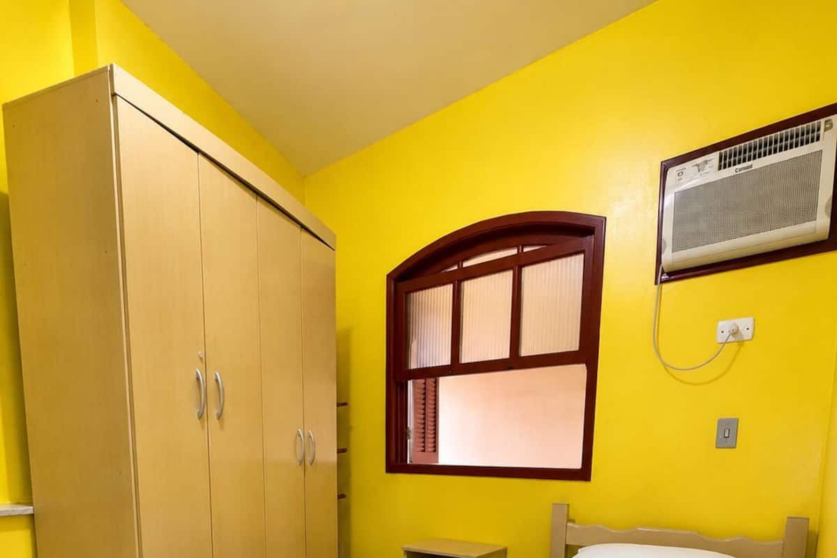 Ein Zimmer mit Bett, Kleiderschrank, Fenster und Klimaanlage.