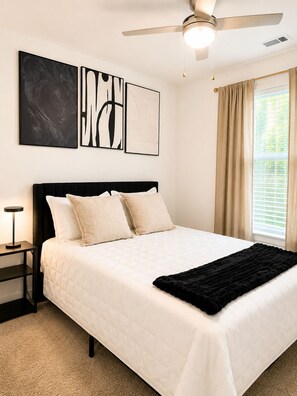 A bedroom with a bed, a ceiling fan, a nightstand, and artwork on the wall. - Luxury Belt Line Retreat l Walk to Ponce City Market & Krog Street (Atlanta)