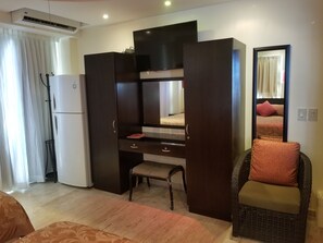 Ein Hotelzimmer mit Bett, Schreibtisch mit Schubladen, Stuhl, Kleiderschrank und einem großen Spiegel.