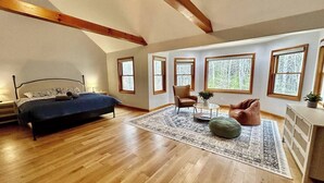 A spacious room with a large bed, a chair, a small table, and a cabinet. - Fire Pit Evenings • Outdoor Dining - Five Acres (Palenville)