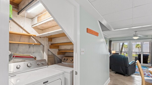 Ein Waschraum mit Waschmaschine und Trockner, Holzböden und einem Deckenventilator.