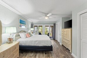 Une chambre à coucher comprenant un lit, un ventilateur de plafond, une commode, un téléviseur et une fenêtre donnant sur l’extérieur.