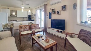 Ein Wohnzimmer mit Fernseher, Holzmöbeln, Essbereich und Küche.