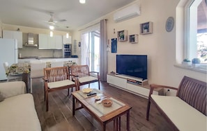 Ein Wohnzimmer mit Fernseher, Holzmöbeln, Essbereich und Küche.