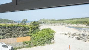 Vista da praia com mesas de piquenique e uma cerca.
