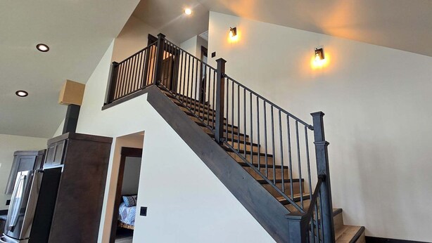 A staircase with a black railing, a white wall, and recessed lighting. - LaLuna Ranch- 4 bedroom mountain-view home on the way to Yellowstone (Cody)