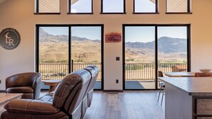 A spacious room with a large sliding glass door leading to a balcony with a mountain view. - LaLuna Ranch- 4 bedroom mountain-view home on the way to Yellowstone (Cody)