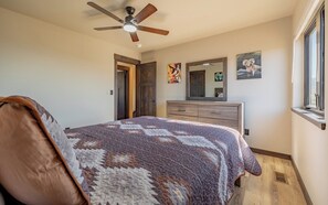Ein Schlafzimmer mit Bett, Deckenventilator, Kommode und Kunstwerk an der Wand.