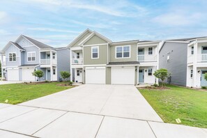 A row of townhouses with a central driveway, front porches, and small front yards. - Beach Glass Bungalow- new build close to beach and park (South Haven)